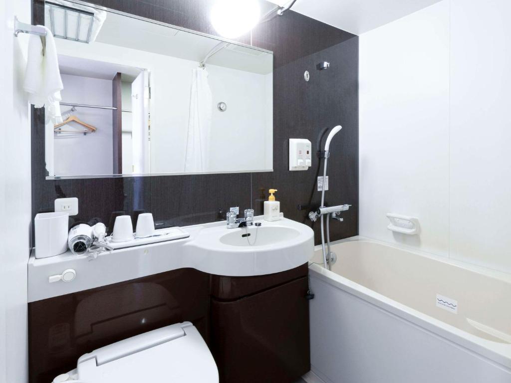 a bathroom with a sink and a toilet and a mirror at Comfort Hotel Central International Airport in Tokoname