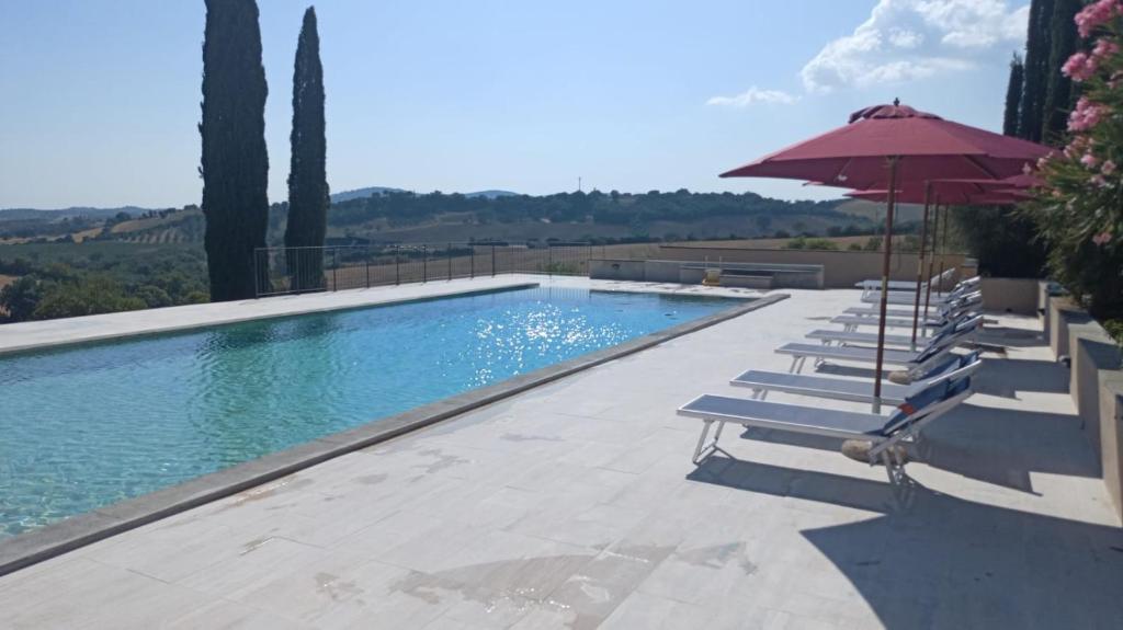 a swimming pool with chairs and an umbrella at Villa Pieve Vecchia in Campagnatico