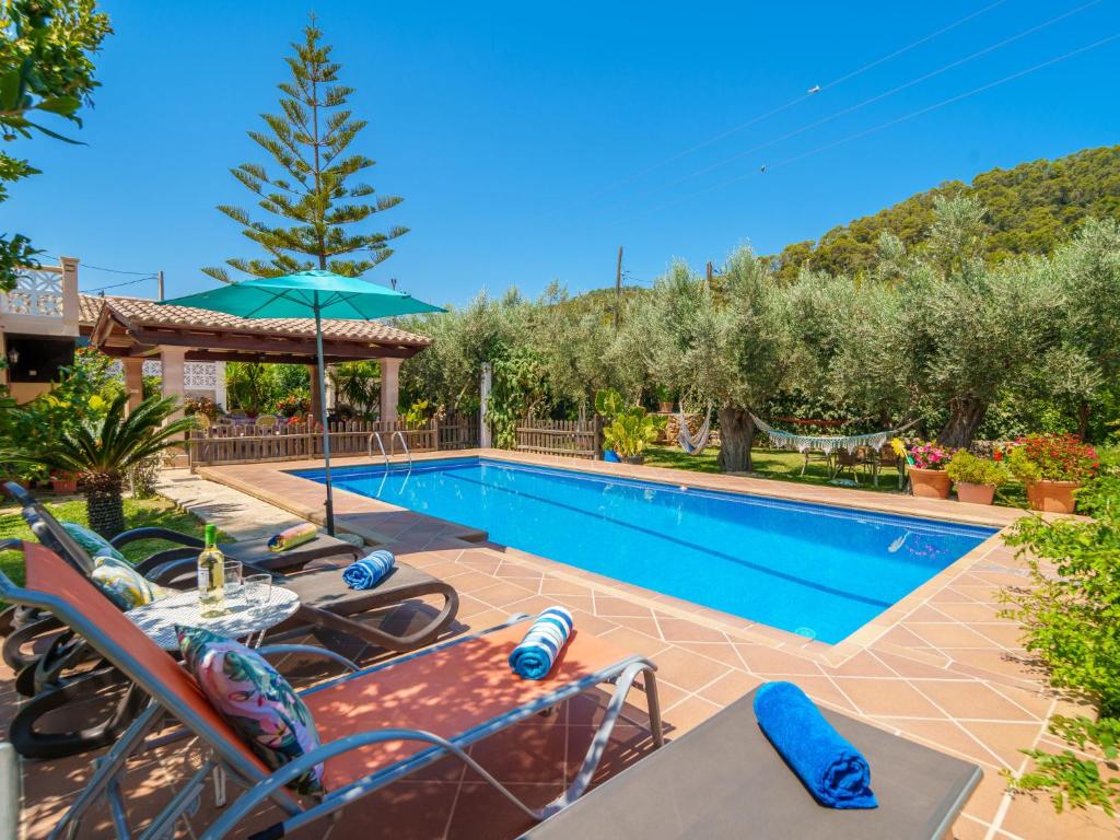 una piscina con sillas, una mesa y una sombrilla en Holiday Home Cas Pobler by Interhome, en Caimari