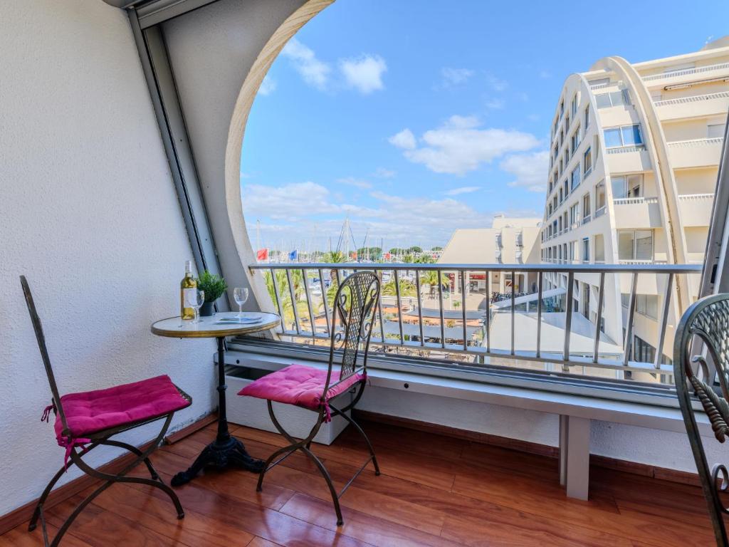 d'un balcon avec deux chaises, une table et une fenêtre. dans l'établissement Apartment Le Suffren-2 by Interhome, au Grau-du-Roi