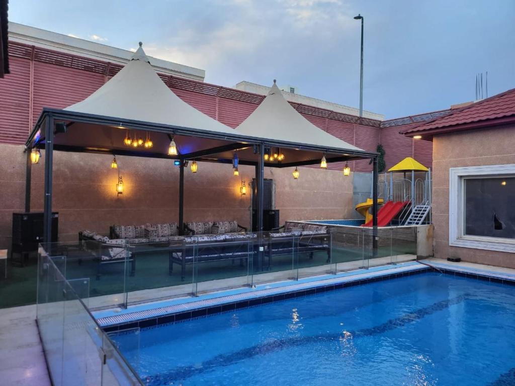 a swimming pool with a pavilion and a table and chairs at شاليهات جولدن الفندقية in Al-Salam