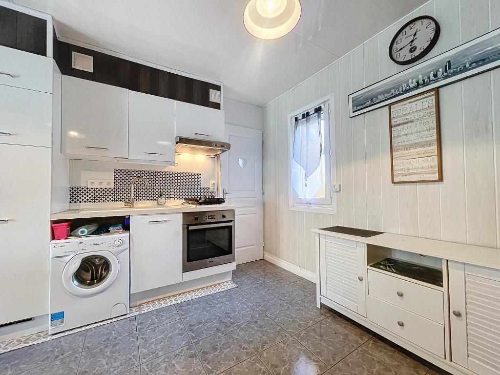 une cuisine avec des armoires blanches et une laveuse et une sécheuse dans l'établissement Le bégonia, à 100m de la plage, à Narbonne