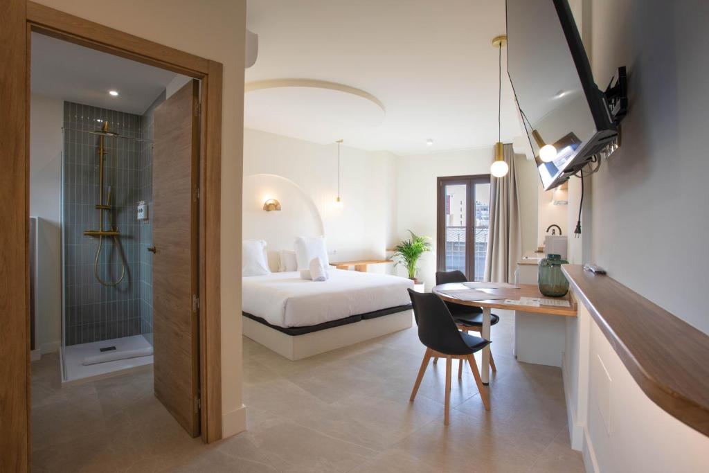 a hotel room with a bed and a desk and a table at Reina Victoria El Mercado in Alicante