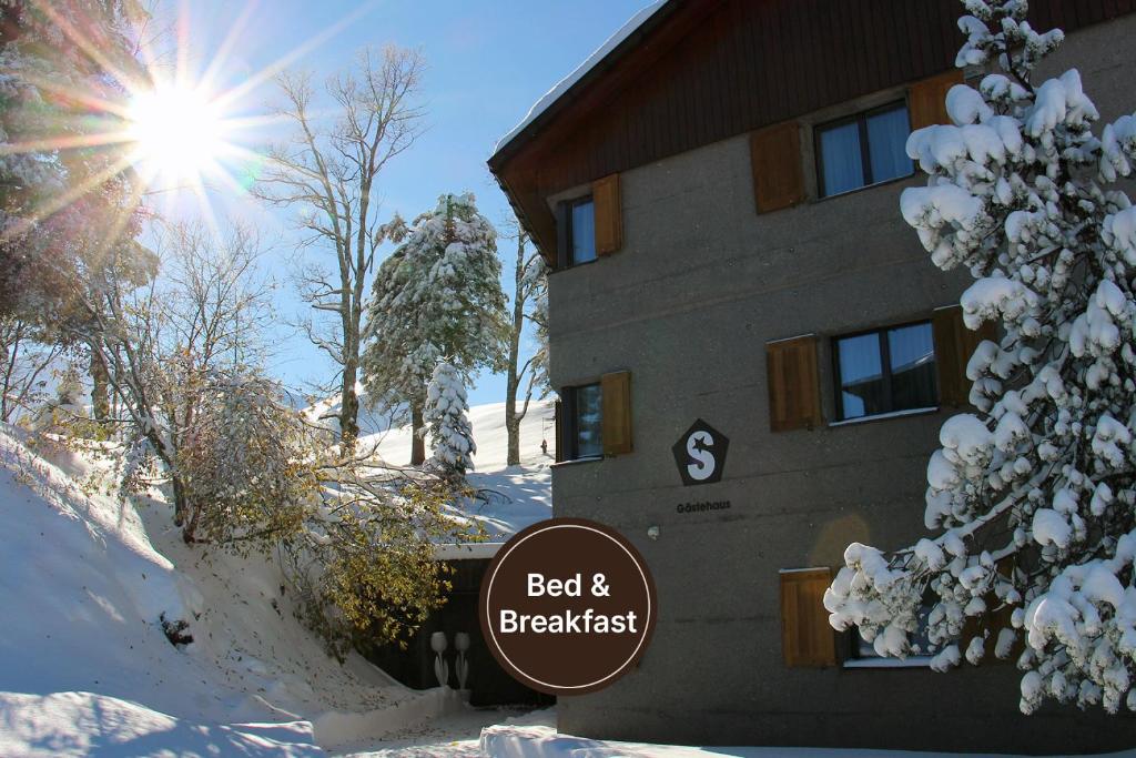 a building with a sign in front of it in the snow at Gästehaus by Stoos Hotels in Stoos