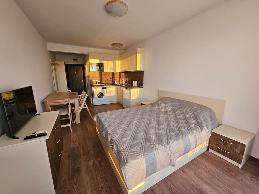 a bedroom with a large bed and a kitchen at Sunset studio in Shartrez in Shkorpilovtsi