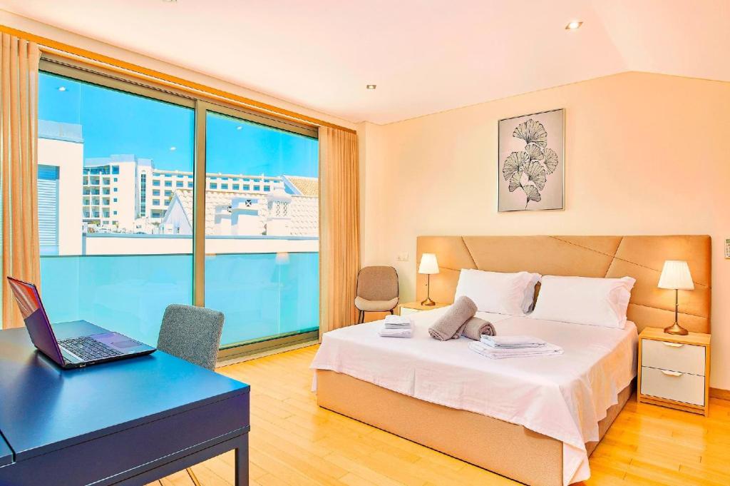 a bedroom with a bed and a desk with a laptop at Stunning Townhouse With Pool In Tavira Centre in Tavira