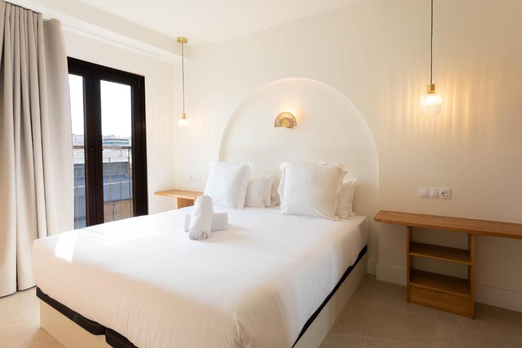 a bedroom with a large white bed with a window at Reina Victoria El Mercado in Alicante