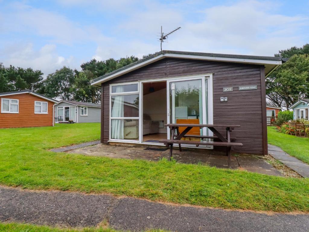a tiny house with a patio and a table at Hawker's Cove in Padstow