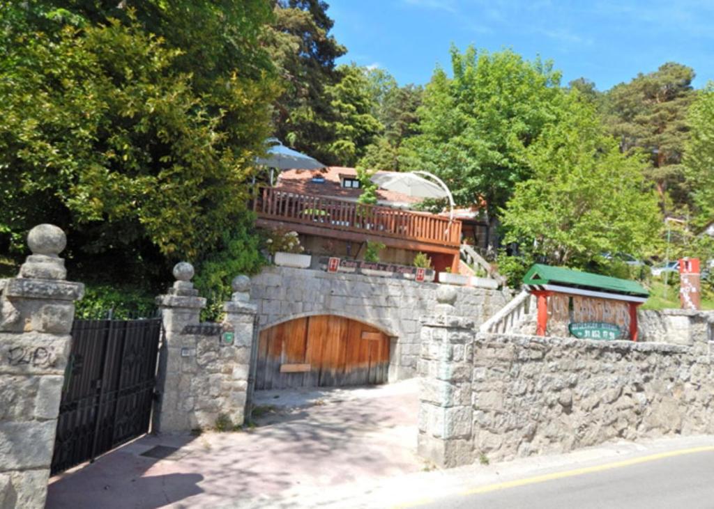 a stone fence with a wooden gate with a wooden door at Espacio Rural Los Castaños in Cercedilla