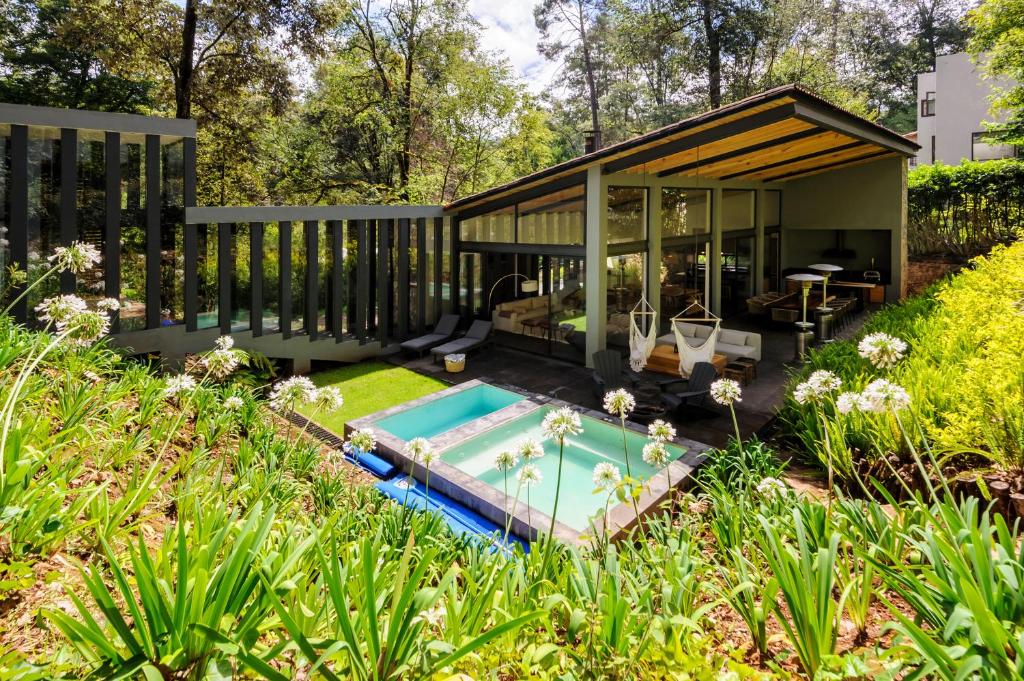 a house with a swimming pool in a garden at Casa Helechos, Arquitectura Única con Vistas al Bosque in Valle de Bravo