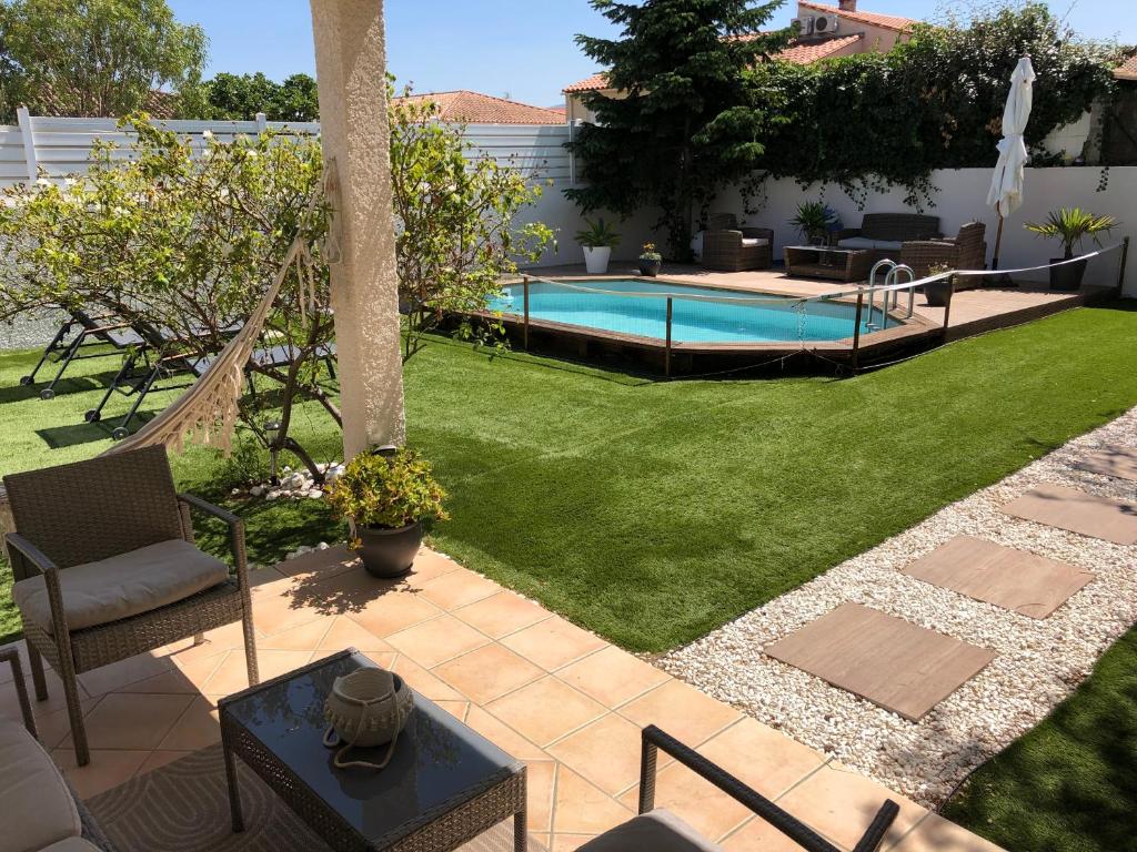 une cour avec un hamac et une piscine dans l'établissement La maison de Julie et Franck, à Montescot