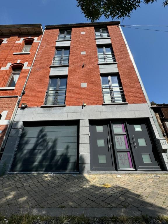un grand bâtiment en briques avec deux portes de garage dans l'établissement L'écrin des Vennes - Liège centre, à Liège
