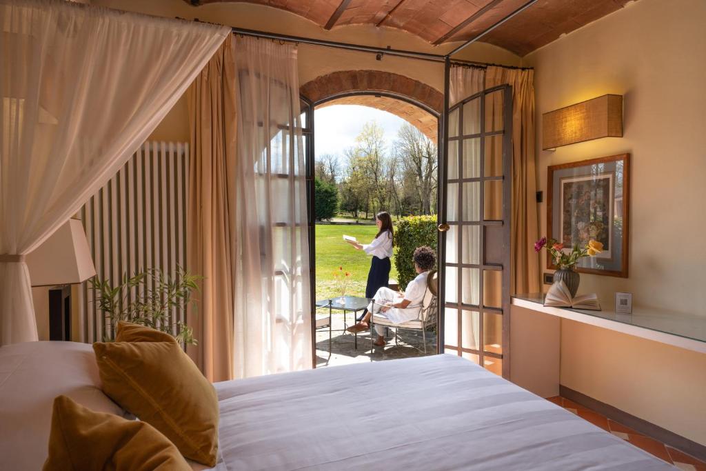 a woman standing outside of a bedroom with a bed at Borgo San Luigi in Monteriggioni