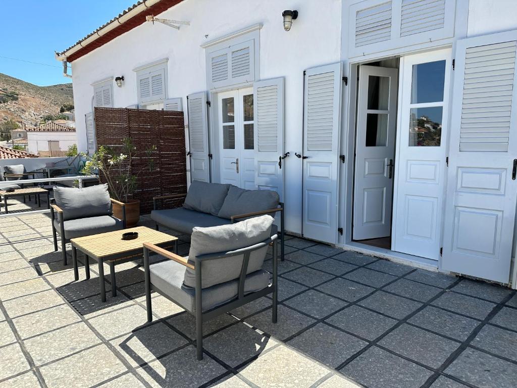 a patio with chairs and a table and a building at Hotel Miranda in Hydra