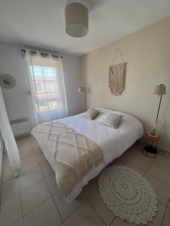 une chambre avec un lit blanc et une fenêtre dans l'établissement Appartement T2 climatisé, à Port-Saint-Louis-du-Rhône