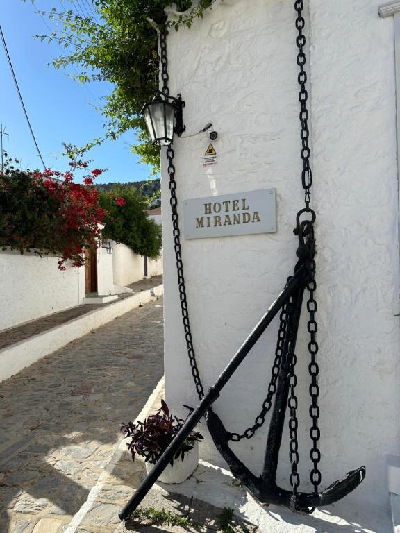 a sign on the side of a building with a chain at Hotel Miranda in Hydra
