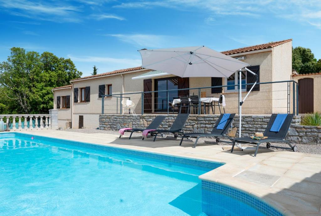 une piscine avec deux chaises et un parasol à côté d'une maison dans l'établissement 34CANTA Le Cantagril, à Argelliers