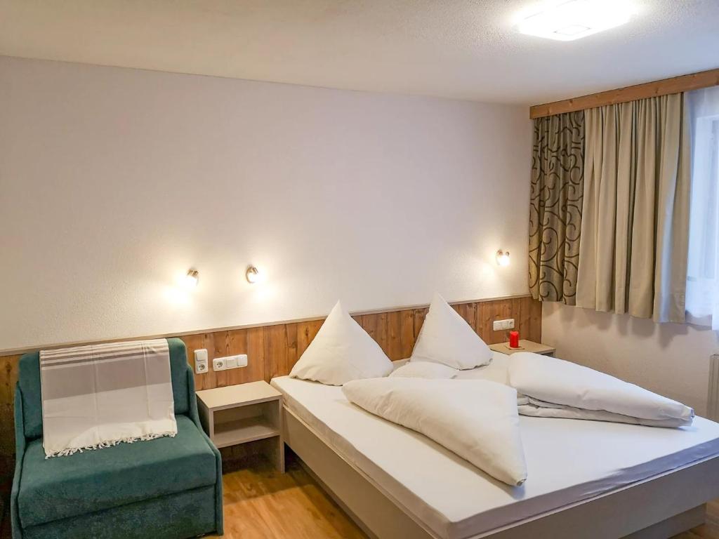 a room with a bed and a green chair at Ferienchalet HOLDERNACH in Kappl