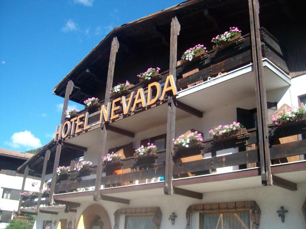 a building with flowerpots and a sign on it at Hotel Nevada in Campitello di Fassa