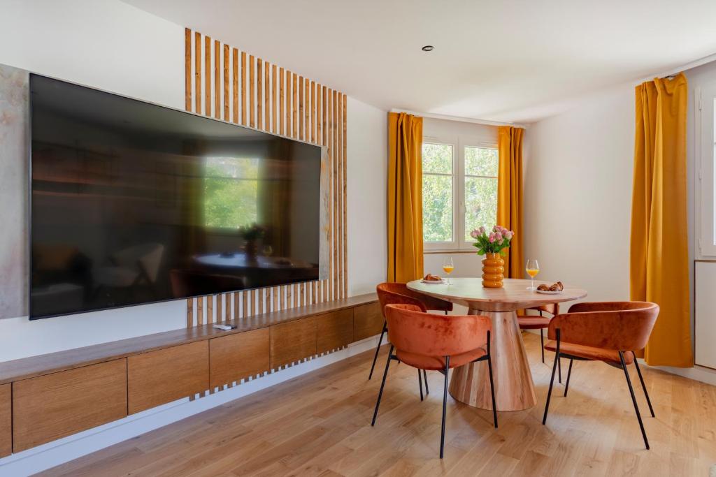 une salle à manger avec une table et une grande télévision dans l'établissement Paris La Defense Design residence, à Courbevoie