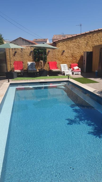 - une piscine d'eau bleue et de chaises rouges dans l'établissement La maison Provençale avec Piscine, à Marseille