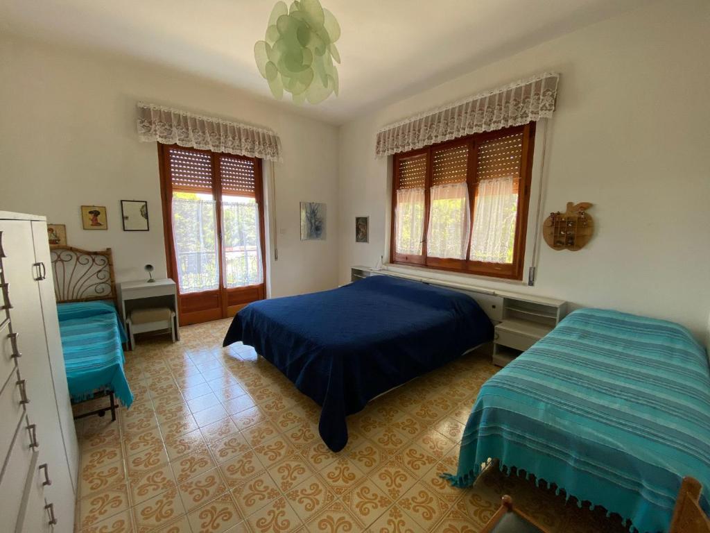 a bedroom with a blue bed and two windows at Villa Sofia San Ciro 401 in Ulmi