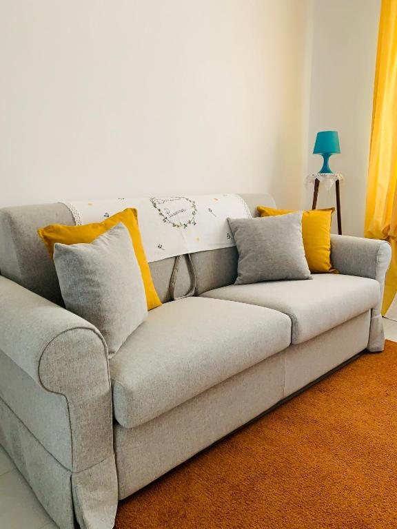 a gray couch with yellow pillows in a living room at Dimora Paesana in Alberobello