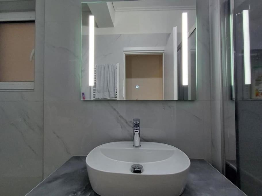 a white sink in a bathroom with a mirror at Modern and comfortable apartment 5km from center in Athens