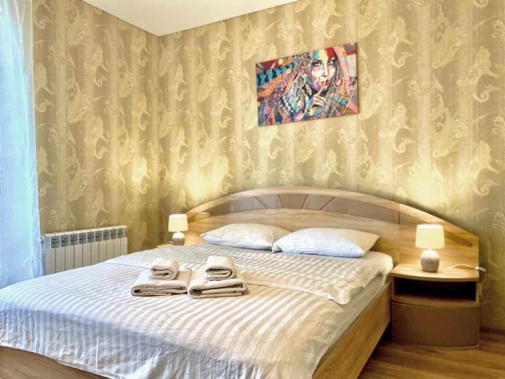 a bedroom with a bed with two towels on it at ApartPoltava НОВИЙ будинок, в самому ЦЕНТРІ 2-ОКРЕМІ кімнати, ПАНОРАМНИЙ БАЛКОН in Poltava