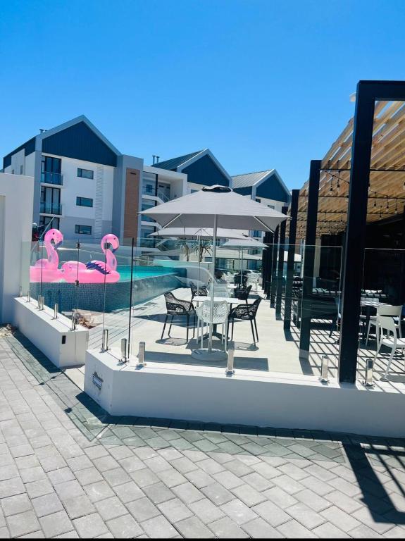 a pool with pink flamingos and a table and an umbrella at The Paramount and The Supreme at Bellamare in Summerstrand