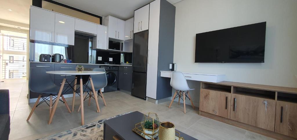 a living room with a kitchen with a tv on the wall at The Paramount and The Supreme at Bellamare in Summerstrand