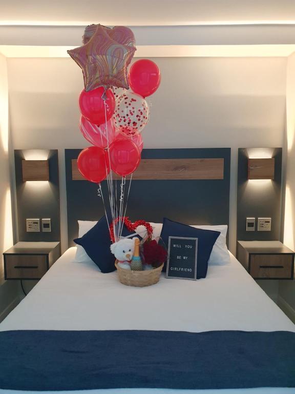 a bed with a bunch of red balloons and a alarm clock at The Paramount and The Supreme at Bellamare in Summerstrand