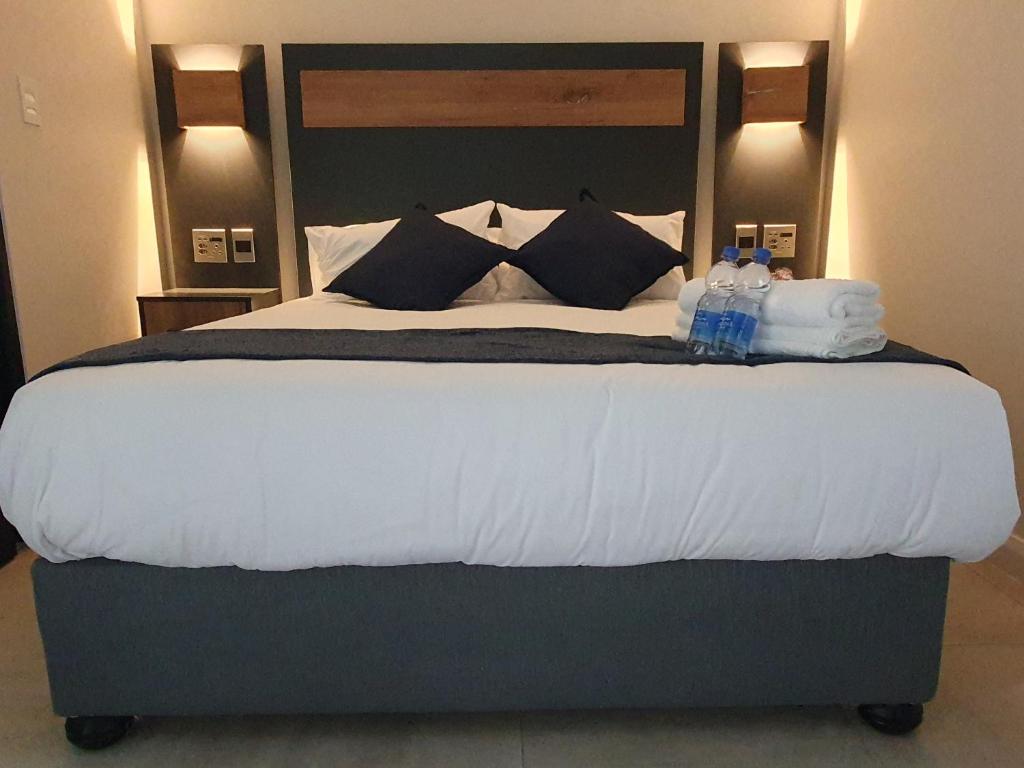 a large bed with two bottles of water on it at The Paramount and The Supreme at Bellamare in Summerstrand