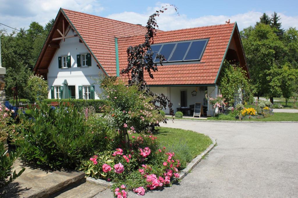 una casa con techo rojo y algunas flores en Buschenschank Orsl, en Wildbach