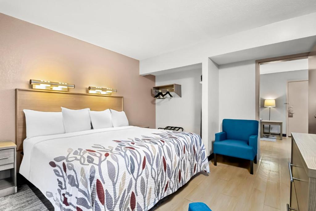 a hotel room with a bed and a blue chair at Red Roof Inn Myrtle Beach Hotel - Market Commons in Myrtle Beach