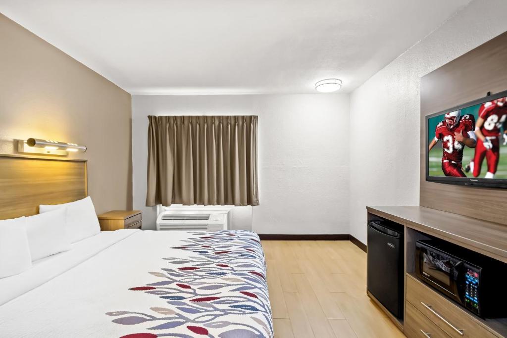 a hotel room with a bed and a flat screen tv at Red Roof Inn Myrtle Beach Hotel - Market Commons in Myrtle Beach