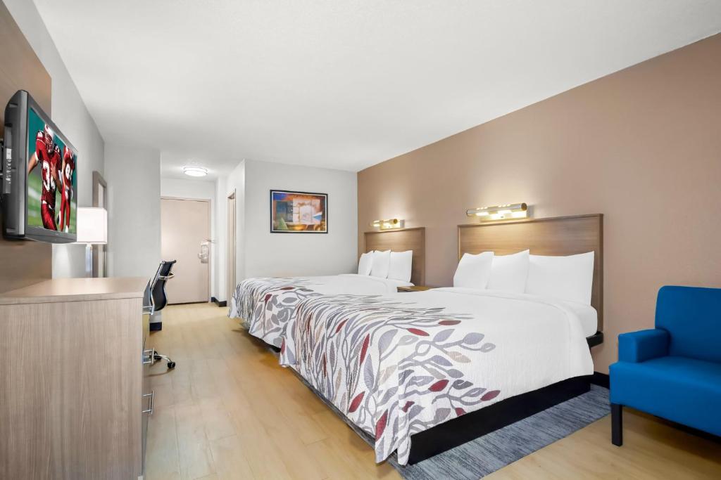 a hotel room with a large bed and a blue chair at Red Roof Inn Myrtle Beach Hotel - Market Commons in Myrtle Beach