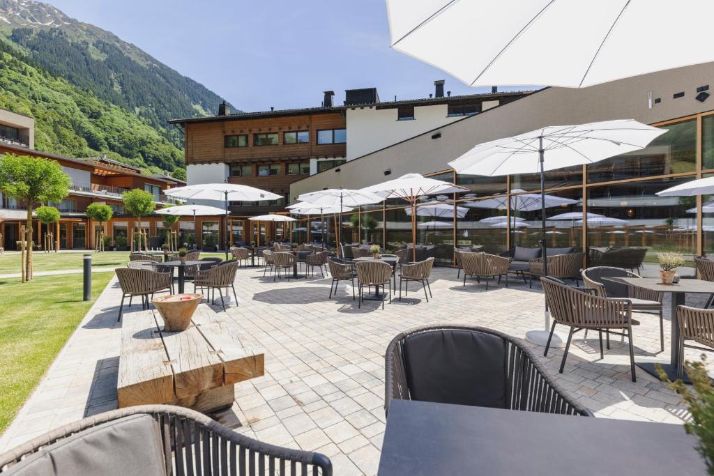 an outdoor patio with tables and chairs and umbrellas at Alpenhotel Montafon & SPA in Schruns