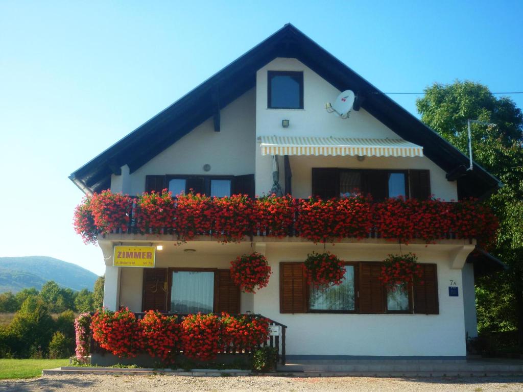 a white house with red flowers on it at House Anamarija in Seliste Dreznicko