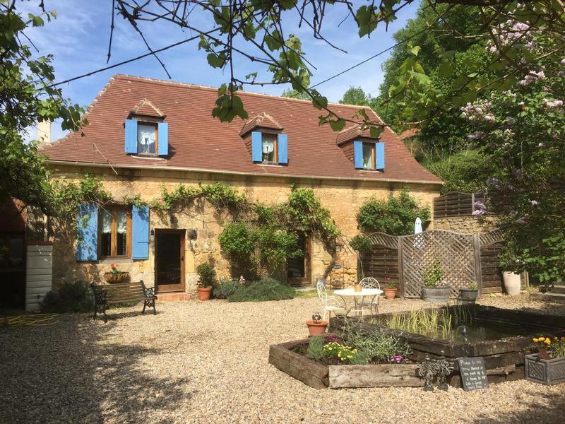 Casa de ladrillo con ventanas azules y patio en Les Girouteaux Le Fenil, en Les Eyzies-de-Tayac