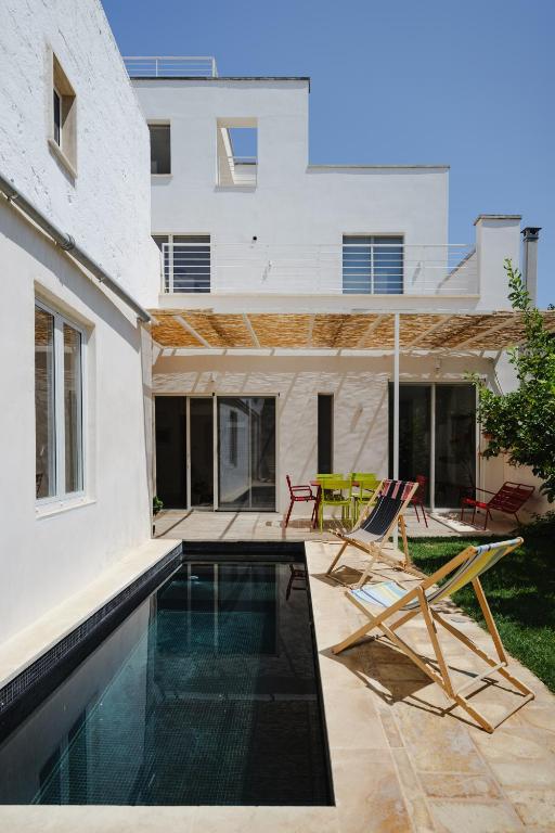 a house with a swimming pool and two chairs at PugliaEclectic - A Modern Oasis in the Heart of Puglia in San Vito dei Normanni