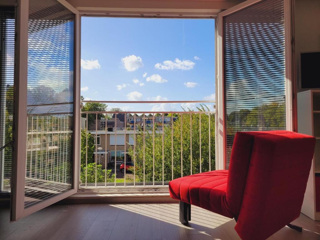 a red chair sitting in front of a large window at Bright room with kitchen in Amsterdam