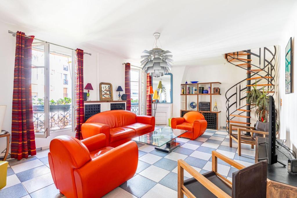 Il comprend un salon doté d'un mobilier orange et d'un escalier. dans l'établissement GuestReady -Logement accueillant proche Montmartre, à Paris