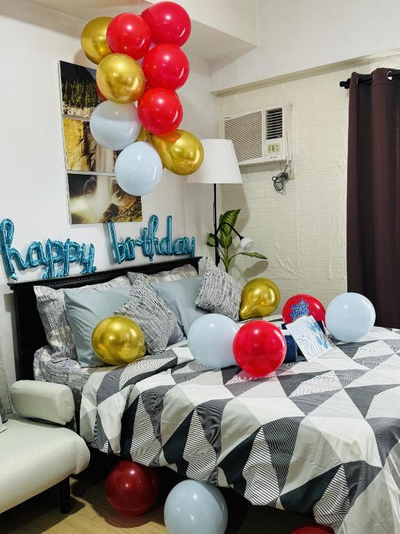 a bed with balloons and a happy birthday sign at Vinia Infinity Studio 1 Near Malls with WiFi and Netflix in Manila