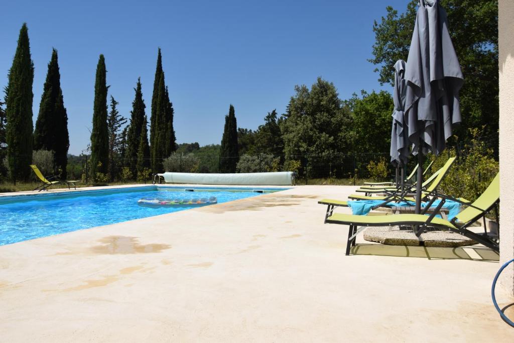 a swimming pool with lounge chairs and an umbrella at Moulin des Gypses Gîte Les Pierres Blanches, Ventoux in Mormoiron