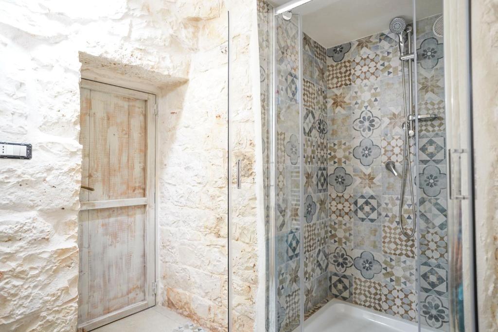 une douche avec une porte en verre dans une salle de bain dans l'établissement Trullo Le Rondinelle, à San Michele Salentino