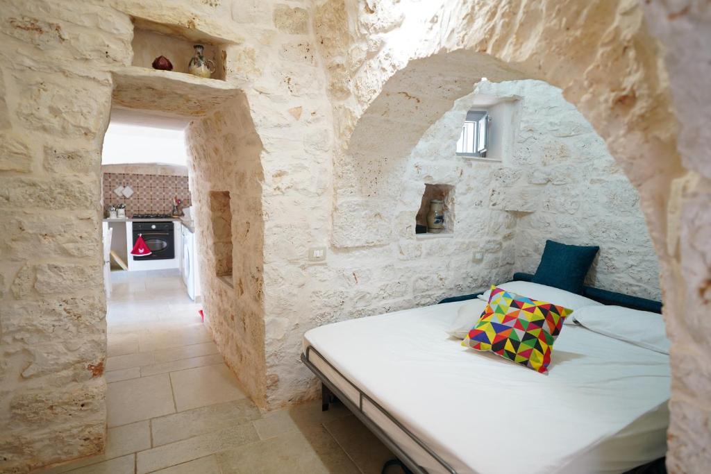 une chambre avec un lit dans un mur de pierre dans l'établissement Trullo Le Rondinelle, à San Michele Salentino