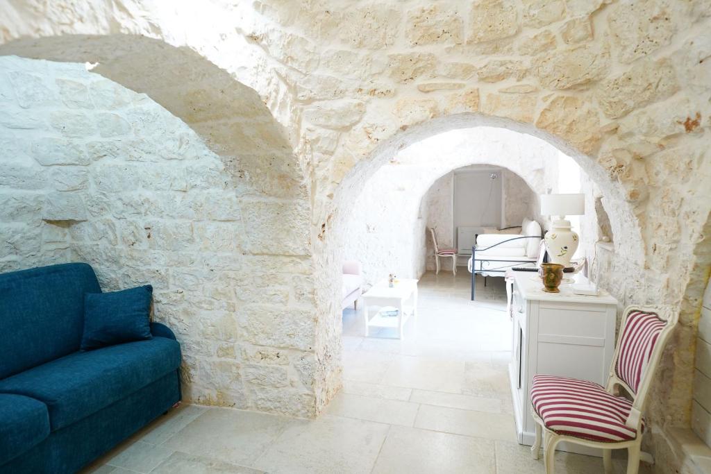 - un salon avec un canapé bleu dans un mur en pierre dans l'établissement Trullo Le Rondinelle, à San Michele Salentino