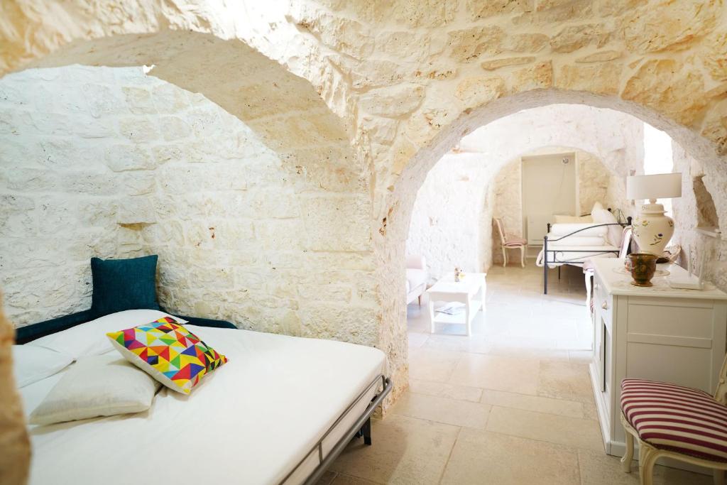 une chambre avec un lit dans un mur de pierre dans l'établissement Trullo Le Rondinelle, à San Michele Salentino 106 autres photos