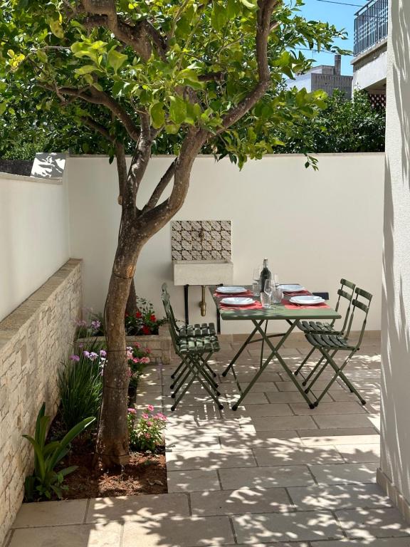 a patio with a table and chairs under a tree at Casetta di Tiggiano - Boutique house in Tiggiano